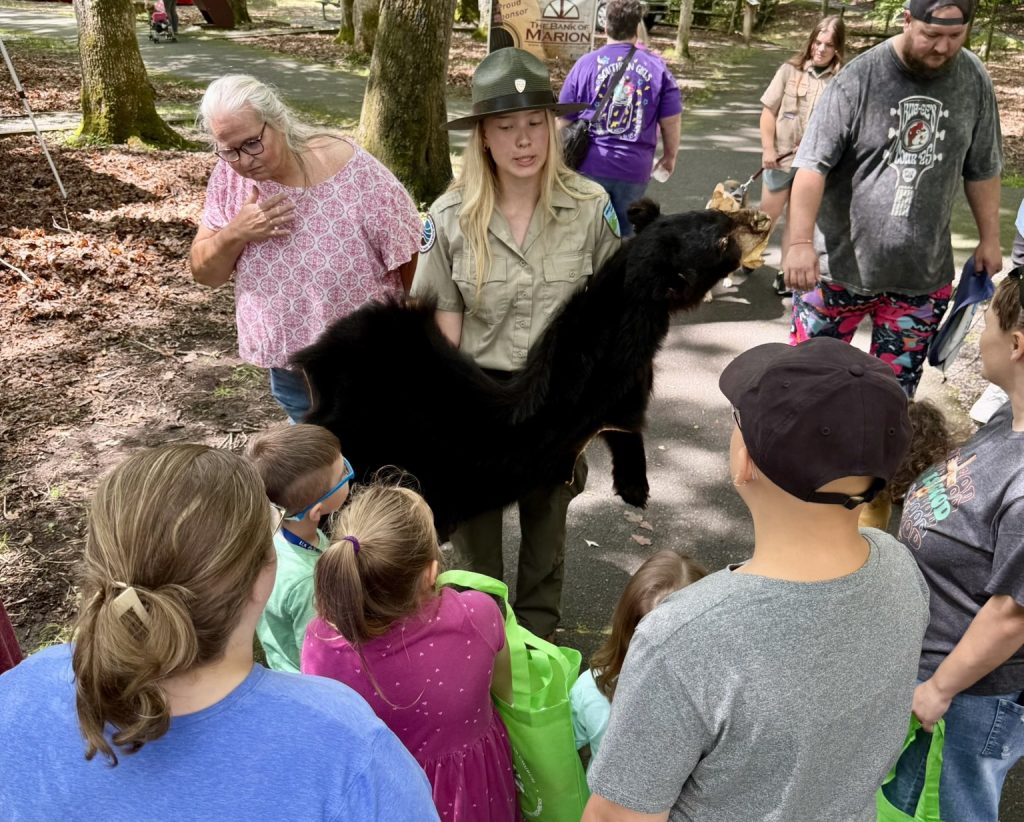 Park ranger showing people stuffed black bear.